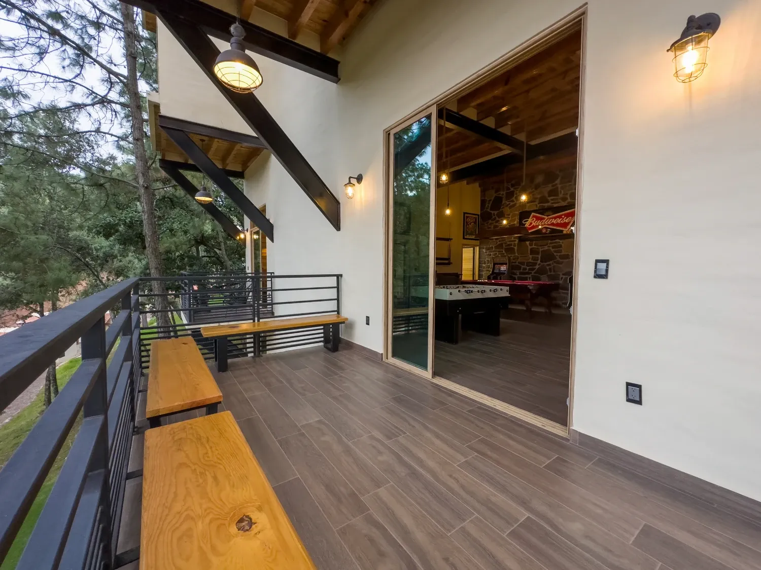 Terraza de madera entre pinos con acceso al salón de juegos con billar y futbolito